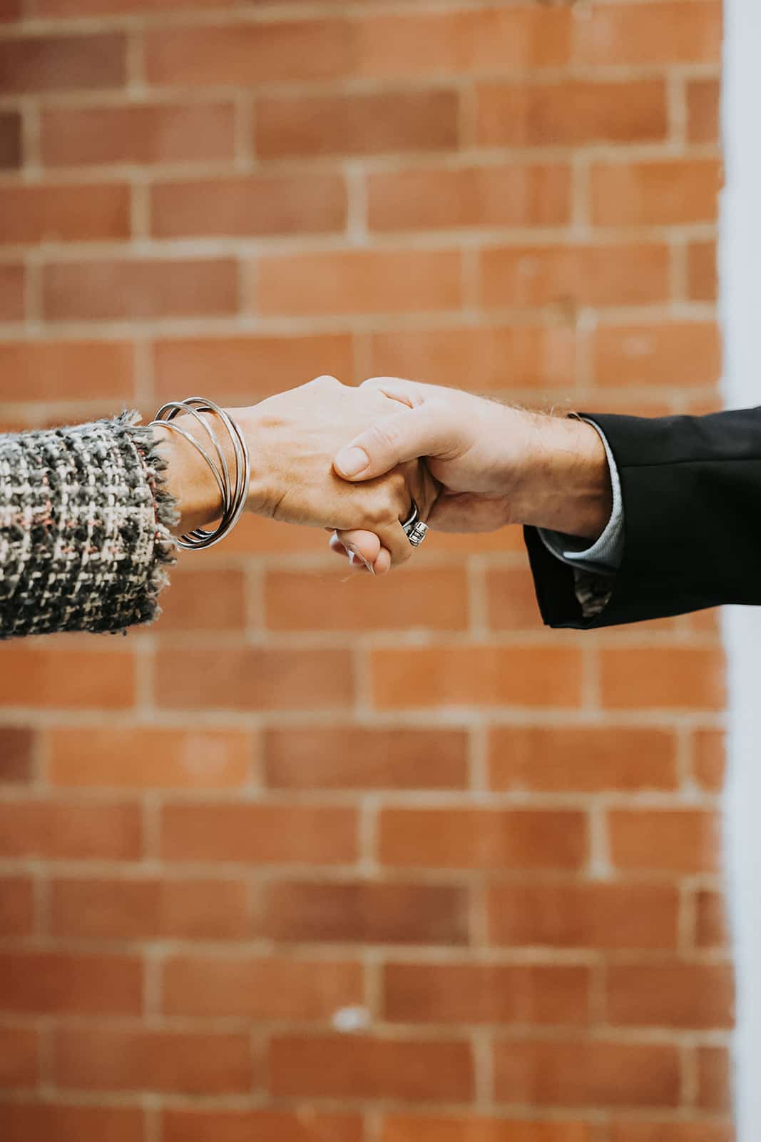 A handshake between a man and woman who is wearing silver bracelets
