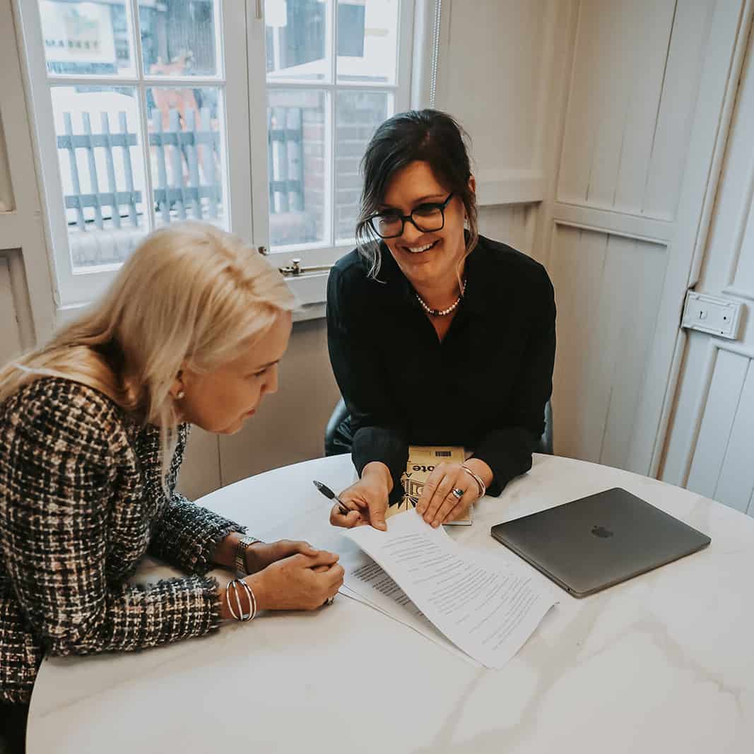 Susie Webb reviewing paperwork with a client at a round white table